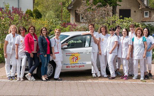 Gruppenbild des Teams der Kirchlichen Sozialstation mit Auto