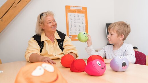 Schulbegleiterin mit Junge besprechen Stimmung mit Smiley-Bällen
