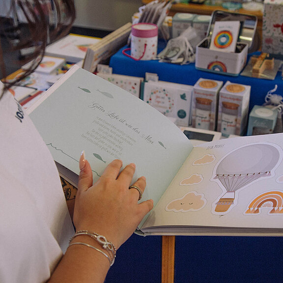 Eine Kundin blättert im Wallfahrtsladen in einem Kinderbuch