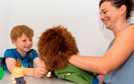 Junge spielt gemeinsam mit einer Frau mit einer Handpuppe