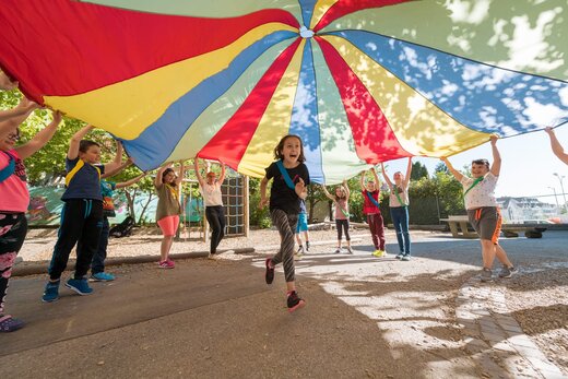 Kinder spielen mit einem Fallschirm-Schwungtuch
