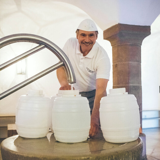Mitarbeiter der Küche befüllt Wasserkanister an der Heiligenbronner Quelle