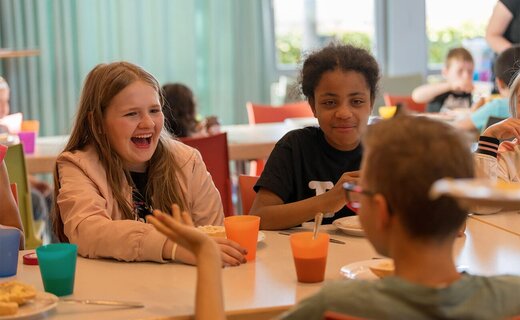 Jugendliche lachen gemeinsam beim Mittagessen im Speisesaal