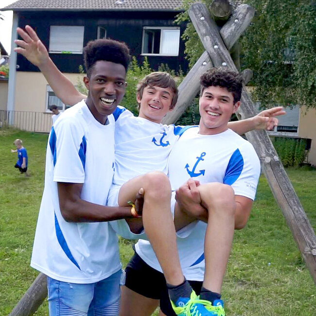Drei Jungs tragen das gleiche Sporttrikot und haben Spaß