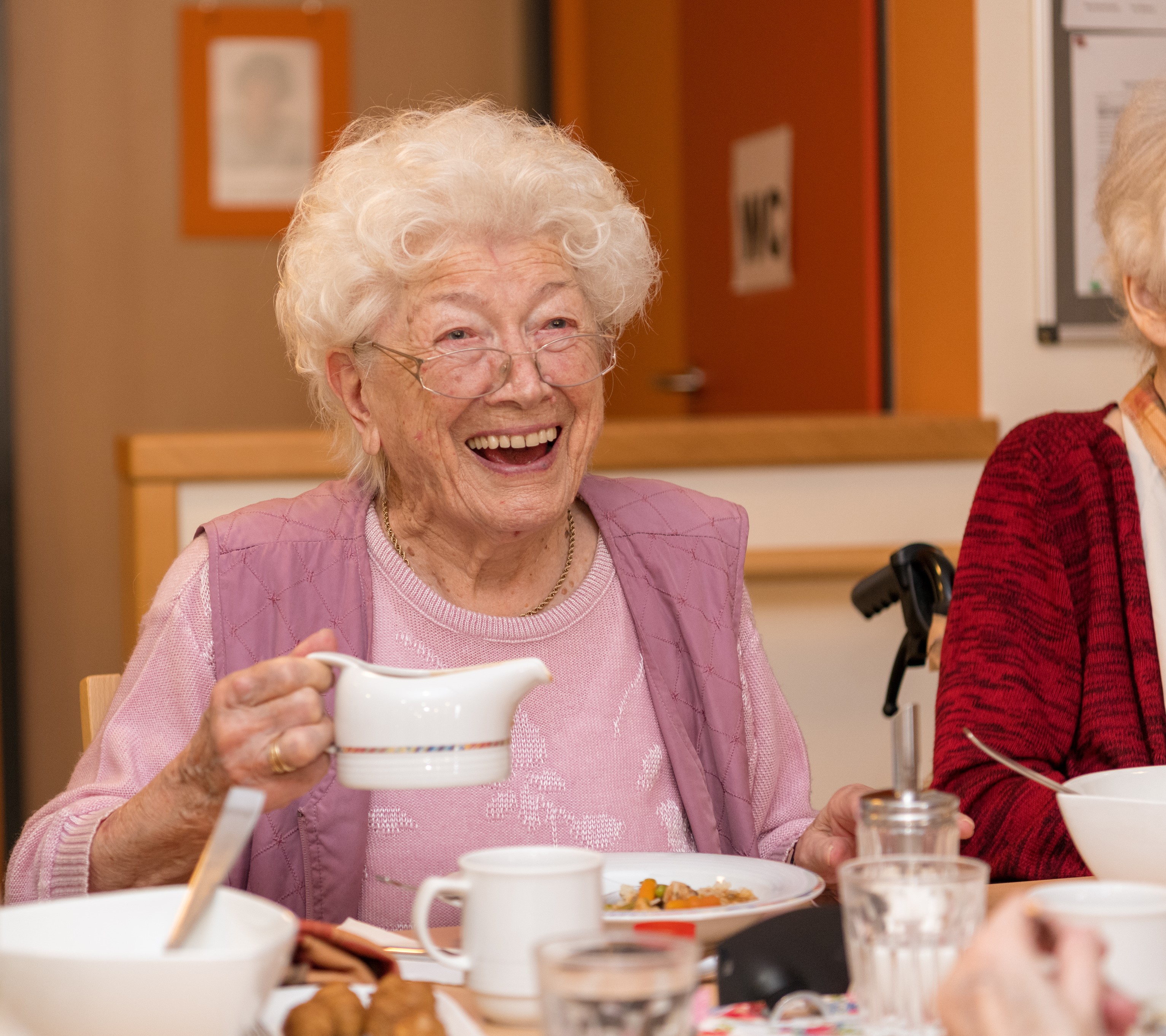 Ältere Dame beim Kaffeetrinken lacht herzlich