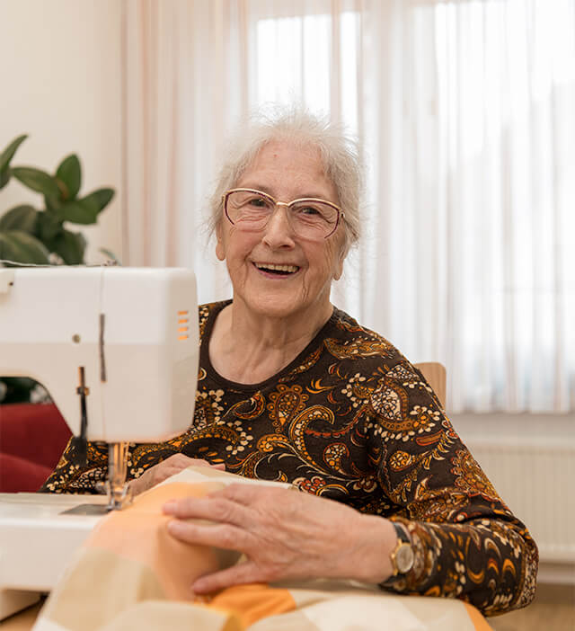 ältere Dame beim Nähen mit einer Nähmaschine