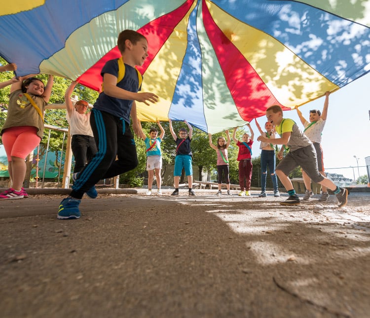 Kinder spielen mit einem Fallschirm-Schwungtuch