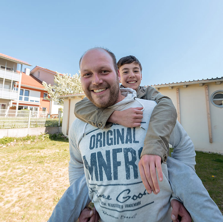 Erzieher trägt Jugendlichen Huckepack