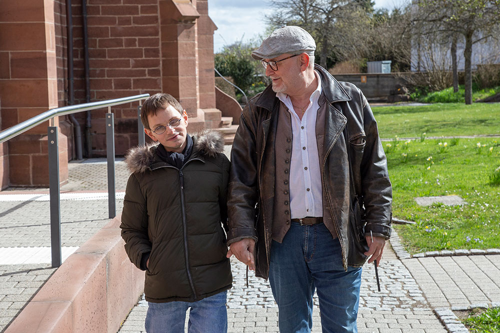 Angehöriger läuft mit einem Junge mit Sehbehinderung übers Gelände