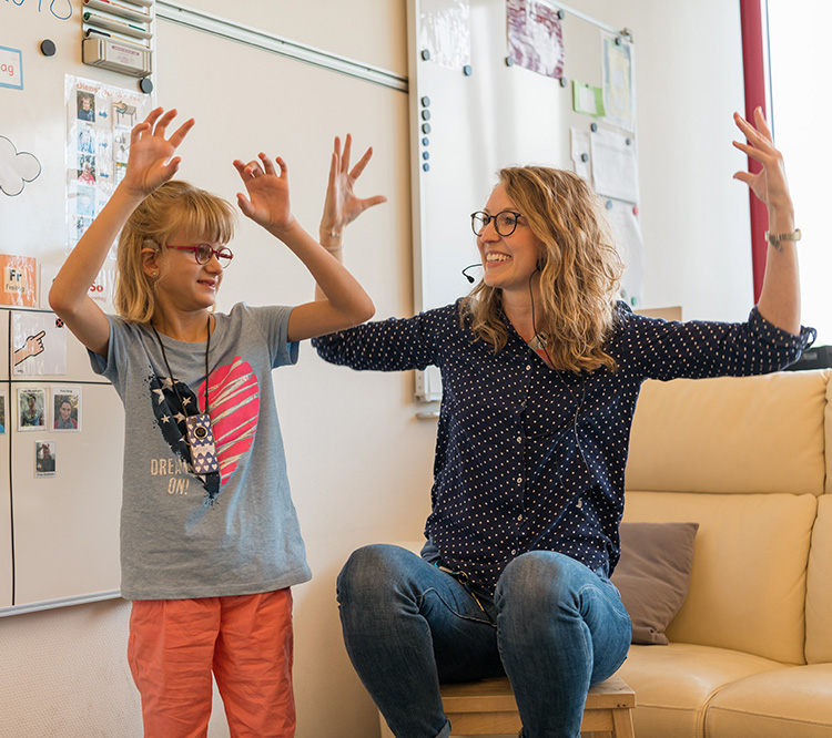 Lehrerin und Schülerin mit Hörbehinderung üben Gebärden
