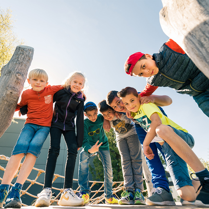 Kinder und Jugendliche bilden einen Halbkreis und lachen nach unten in die Kamera