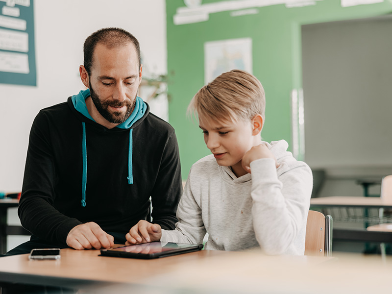 Jugendlicher und Betreuer zusammen in der Schule am Tisch