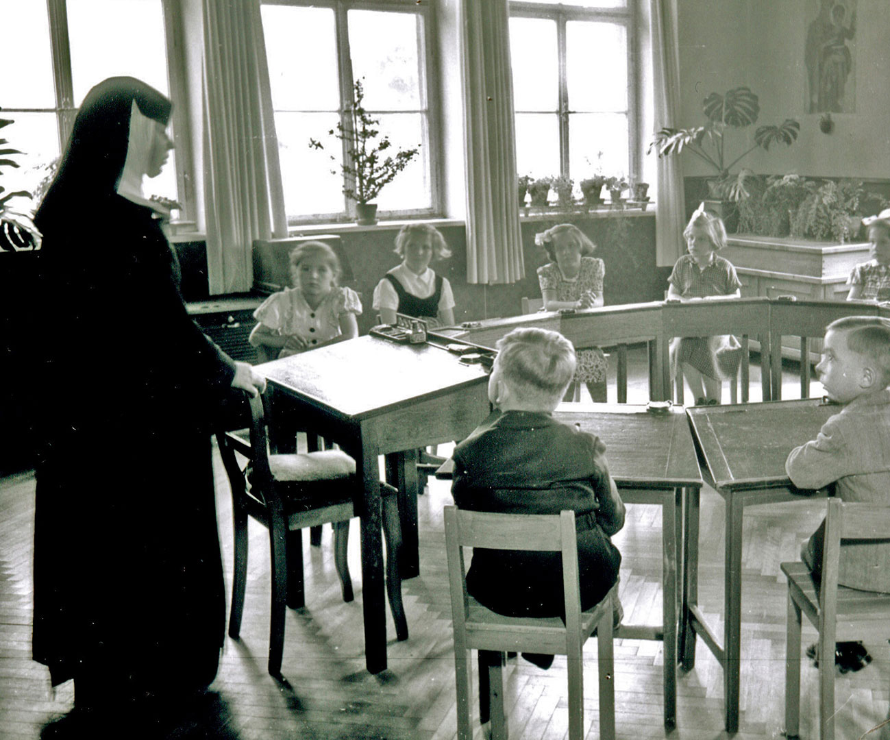 Schwarz-Weiß-Bild aus Klosterzeiten: Schwester unterrichtet Schüler im Halbkreis